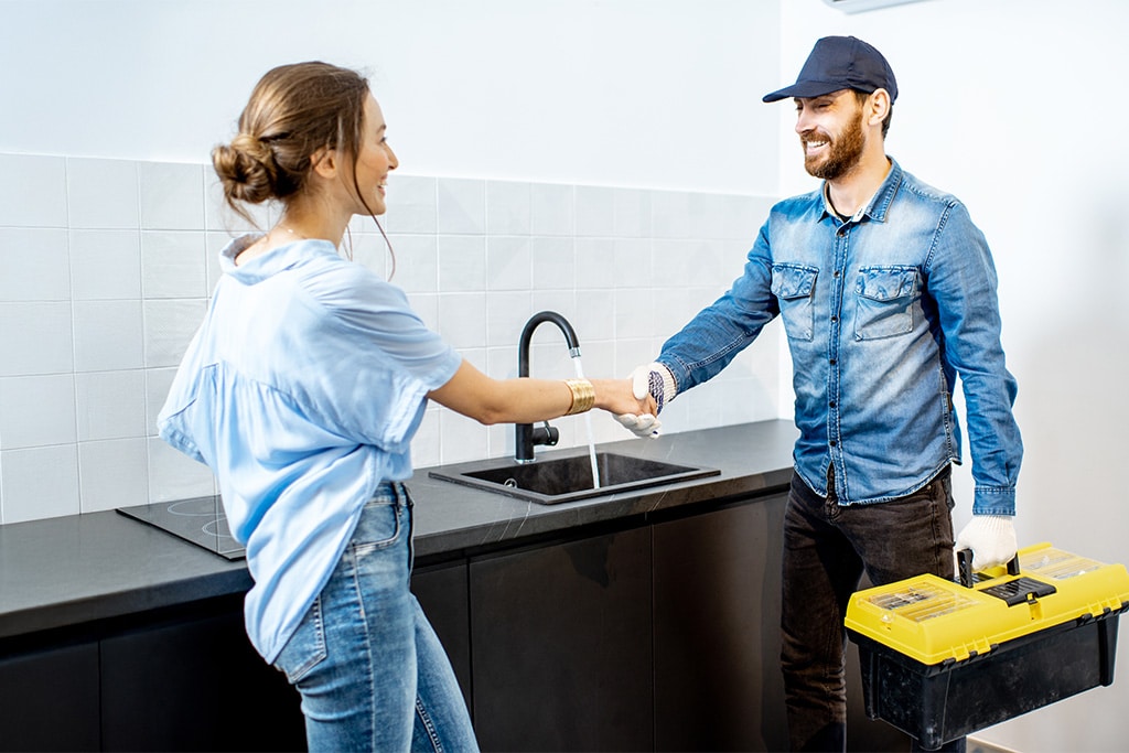 Technician completing a water system installation with a satisfied homeowner